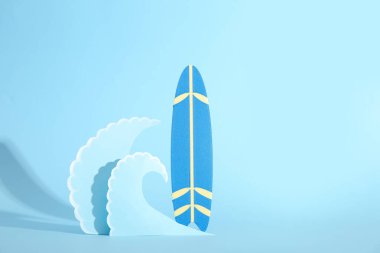 Mini sörf tahtası ve mavi zemin üzerinde kağıt dalgaları olan yaratıcı kompozisyon