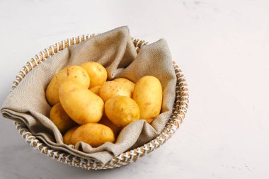 Beyaz arka planda çiğ bebek patatesli hasır kase.