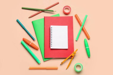 Soluk turuncu arkaplanda farklı kırtasiye malzemesi olan defterler