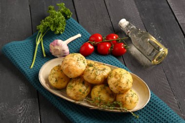 Bir tabak haşlanmış patates, dereotlu ve ahşap kaplama domatesli.