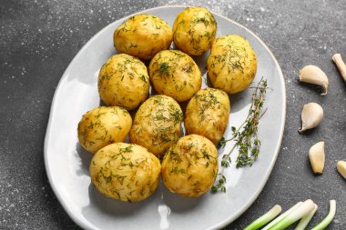 Gri arka planda dereotlu ve sarımsaklı haşlanmış bebek patatesler.