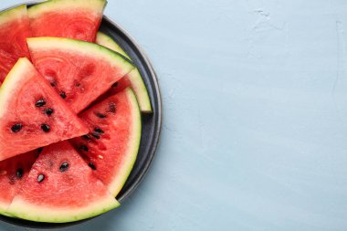 Mavi zemin üzerinde taze karpuz parçaları olan bir tabak.
