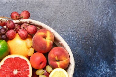 Mavi arka planda farklı taze meyvelerle dolu bir sepet.