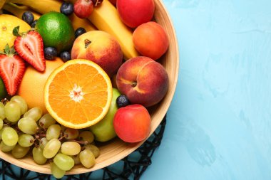 Mavi arka planda farklı taze meyvelerle dolu bir kase.