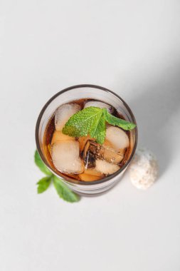 Bir bardak soğuk Küba kokteyli ve beyaz arka planda deniz kabuğu.