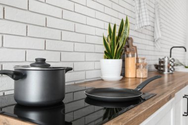 Kızartma tavalı ve elektrikli ocakta pişirme kabı olan modern mutfak, yakın plan.