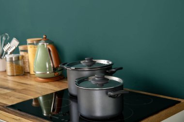 Ahşap mutfak tezgahı ve elektrikli ocakta tencereler.