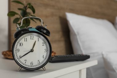 Yatak odasındaki komodindeki çalar saat, yakın plan.