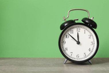 Yeşil duvarın yanındaki masada alarm saati, yakın plan.