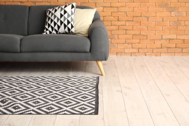 Modern oturma odasının içinde şık bir halı ve gri kanepe var.