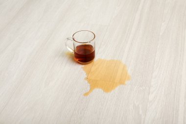 Ahşap kaplama döşeme, fincan ve dökülmüş çay.