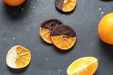 Çikolata soslu kurumuş portakal dilimleri siyah arka planda.