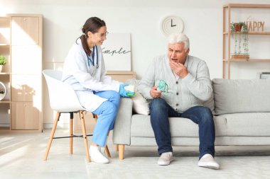 Evde nebulizörü ve hemşiresi olan yaşlı bir adam var.