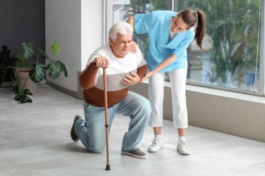 Hastane koridorunda sopa ve hemşire taşıyan hasta kıdemli bir adam.