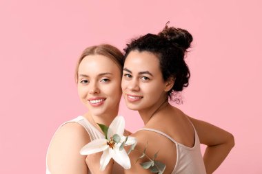 Pembe arka planda zambak çiçeği ve okaliptüs olan güzel genç kadınlar.