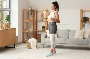 Spor salonunda spor paspası ve su şişesi olan Afro-Amerikan bir kadın.
