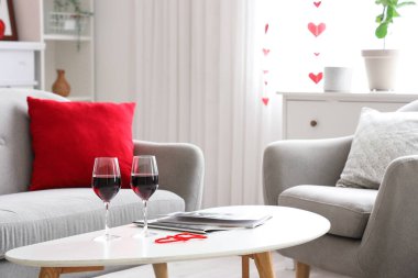 Sehpanın üzerinde şarap bardakları olan şenlikli bir salon. Sevgililer Günü kutlaması