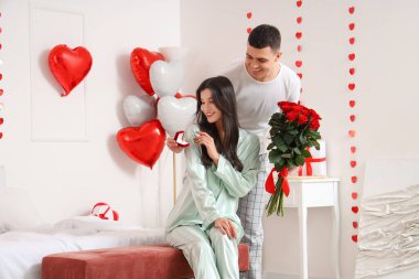 Genç adam yatak odasında kız arkadaşına evlenme teklif ediyor. Sevgililer Günü kutlaması