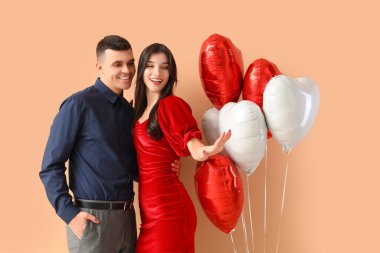 Evlilik yüzükleri ve bej arka planda kalp şeklinde balonları olan genç nişanlı bir çift. Sevgililer Günü kutlaması