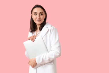 Pembe arka planda dizüstü bilgisayarı olan genç bir iş kadını.