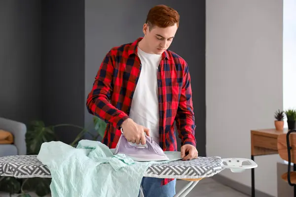 stock image Handsome young man ironing clothes in laundry room