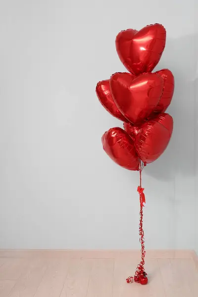 Heart-shaped balloons near grey wall. Valentine\'s Day celebration