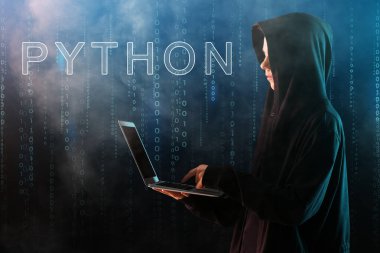 Koyu arkaplanda dizüstü bilgisayarı olan profesyonel bir hacker.