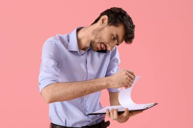 Pembe arka planda cep telefonuyla konuşan genç bir işadamı