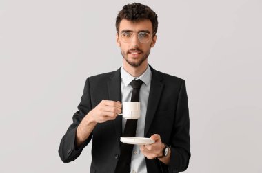 Takım elbiseli genç bir işadamı ve arka planda bir fincan kahve.