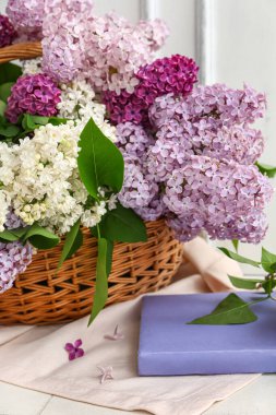 Beyaz ahşap duvarın yanında güzel kokulu leylak çiçekleri olan sepet.