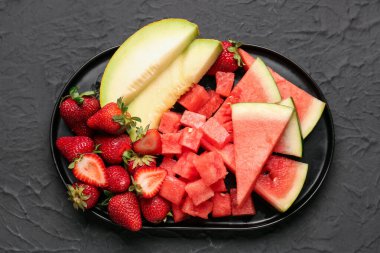 Taze karpuz parçalarıyla dolu tepsi ve siyah arkaplanda farklı böğürtlen