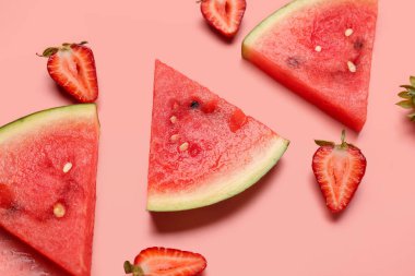 Pembe arka planda taze karpuz ve çilek parçaları.