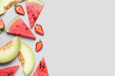 Taze karpuz parçaları ve gri arkaplanda farklı meyveler.