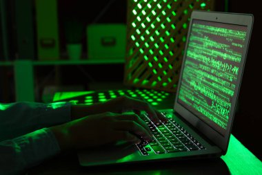 Kadın programcı gece ofiste dizüstü bilgisayarda daktilo kullanıyor.