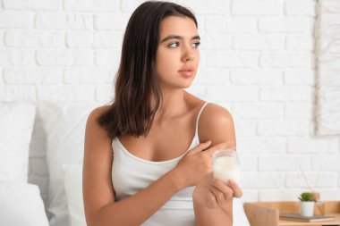 Güzel genç bir kadın evinde hindistan cevizi yağı sürüyor.