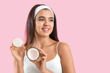 Pembe arka planda hindistan cevizi yağı olan güzel genç bir kadın.