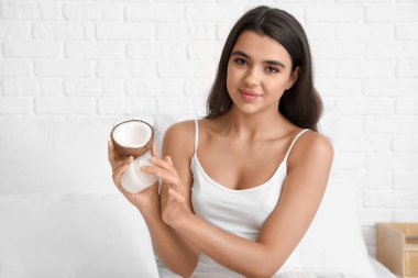 Güzel genç bir kadın evinde hindistan cevizi yağı sürüyor.