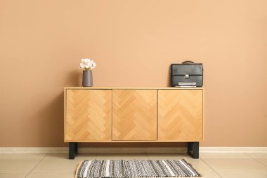 Odada bej duvarın yanında çiçekli ve çantalı TV standı