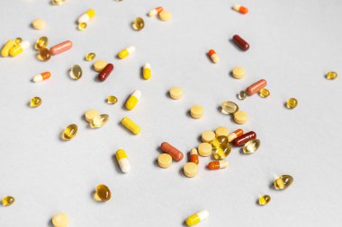 Balık yağı kapsülleri ve gri arka planda farklı haplar.