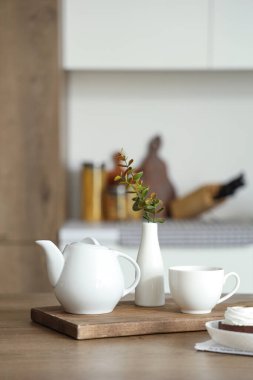 Çaydanlık, fincan ve okaliptüs dallarıyla modern kahvaltı sehpası.