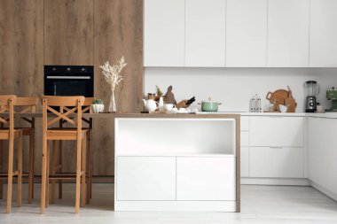 Modern mutfakta kahvaltı masası ve vazosu olan ahşap bir ada.