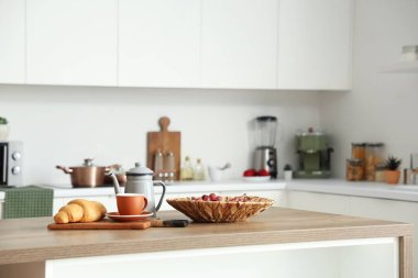 Modern mutfakta üzümlü mutfak masası, çay ve kruvasan.