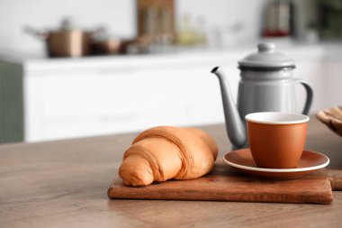 Mutfak masasında çaydanlık, çay ve kruvasan modern mutfakta.