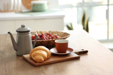 Modern mutfakta üzümlü mutfak masası, çay ve kruvasan, yakın plan.