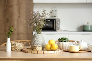 Modern mutfakta kurutulmuş lavanta, limon ve çay setiyle ahşap masa.