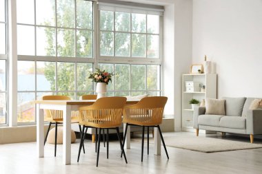 Yemek masasında vazo olan ışık odasının içinde.