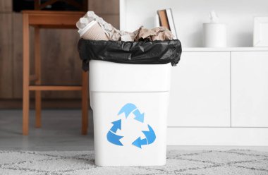 Mutfakta çöp kutusu ve geri dönüşüm logosu var.