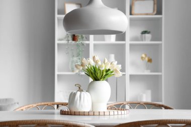 Işık odasındaki yemek masasında güzel lale çiçekleri olan vazo.