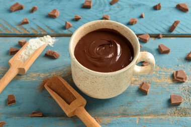 Mavi ahşap arka planda bir fincan lezzetli erimiş çikolata.