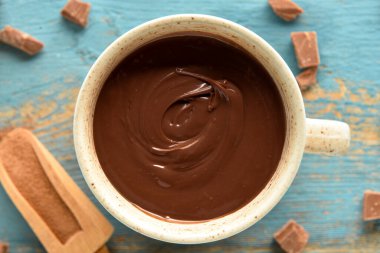 Mavi ahşap arka planda bir fincan lezzetli erimiş çikolata.